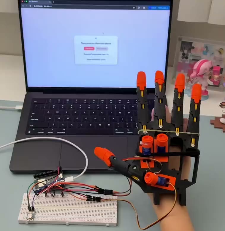 A robotic hand wired to a breadboard in front of a laptop